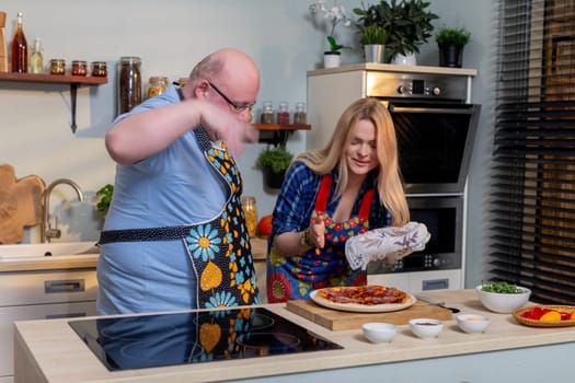 A joyful cooking scene with two individuals creating a delicious meal together with enthusiasm and happiness