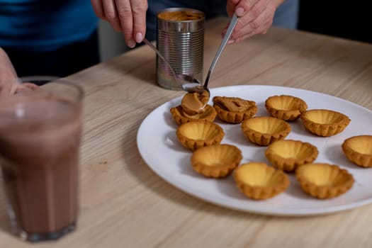 Delicious mini tarts are being served up alongside a refreshing glass of rich chocolate drink on a rustic wooden table