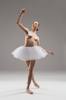 Attractive young slim female in ballet tutu skirt and with sticky tapes on breast posing in studio