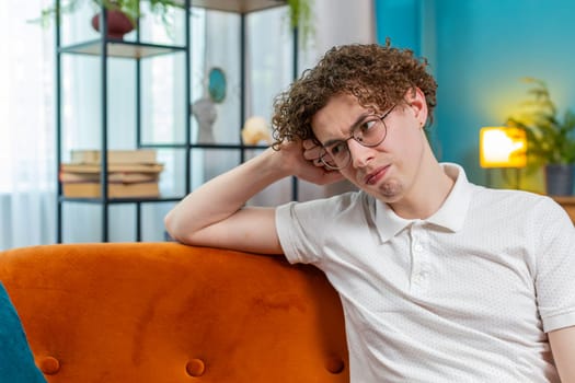 Thoughtful Caucasian man guy male sitting at home looks pensive thinks over life concerns or unrequited love, suffers from unfair situation. Problem, break up, depressed feeling bad annoyed, burnout.