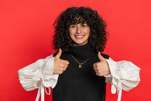 Like. Caucasian woman raises thumbs up agrees with something or gives positive reply recommends advertisement likes good idea feedback celebrating success victory. Girl isolated on red background