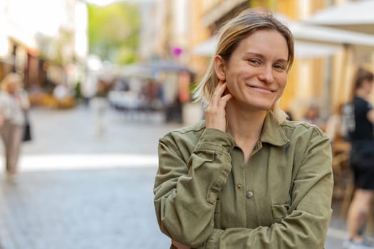 Portrait of happy young woman face smiling friendly glad expression looking at camera resting relaxation feel satisfied good news outdoors. Pretty blond adult girl tourist traveler on city street.