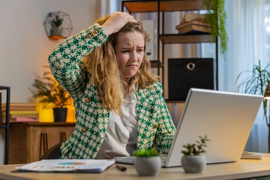 Displeased sad woman using laptop notebook typing browsing working loses becoming surprised sudden lottery results bad news fortune loss game fail computer virus. Caucasian girl at home office table.