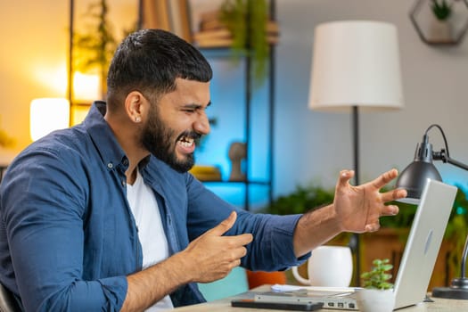 Conflict quarrel negotiation. Angry Hispanic freelancer man making webcam laptop online video call at home office. Upset mad manager talking conversation analyzing financial report mistake problem.