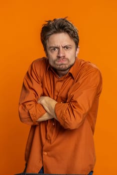 Upset frustrated annoyed man raising hands in indignant expression, quarreling asking reason of conflict problem, why such stubborn. Irritated young guy isolated on orange background indoors. Vertical