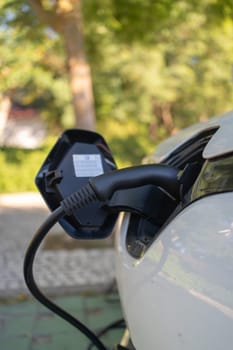 Closeup shot of an EV charger handle connected to electric car at charging station, highlighting sleek design and technology as vehicle powers up for its next journey
