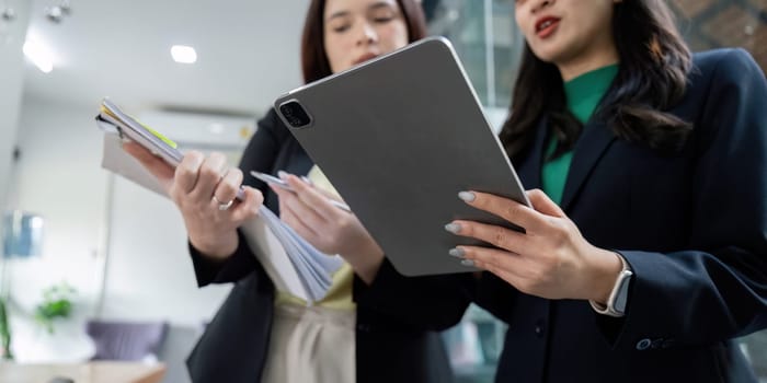 A diverse group of female professionals discusses project strategies and analyzes data, showcasing collaboration in a bright and modern workspace.