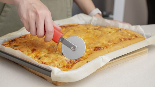 Cutting pizza with a round cutter knife. Close-up of delicious pizza being cut into pieces. Slow motion slicing a pizza into multiple slices with a cutter