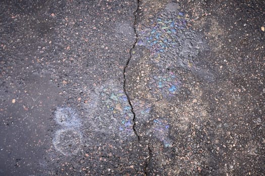 Gasoline or oil spill creating rainbow colors on asphalt road surface