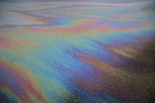 Gasoline rainbow creating colorful patterns on asphalt road