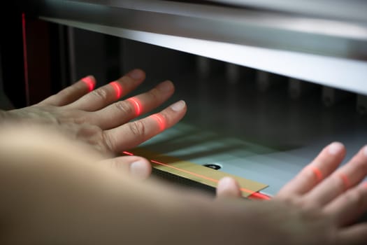 Crop unrecognizable female employee checking and setting up modern digital paper cutting machine in workshop