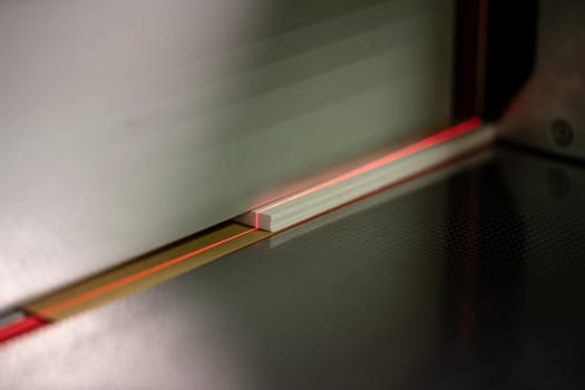 Crop of laser line on paper of modern digital cutting machine in workshop