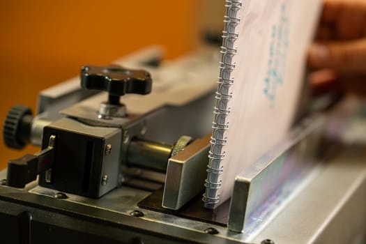 Paper spiral notepad between iron parts of professional machine tool in modern workplace