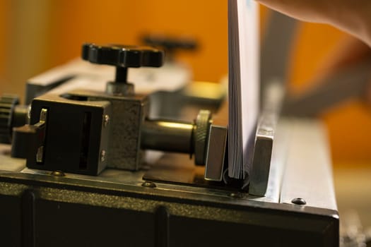 Paper spiral notepad between iron parts of professional typograohy machine tool in modern workplace
