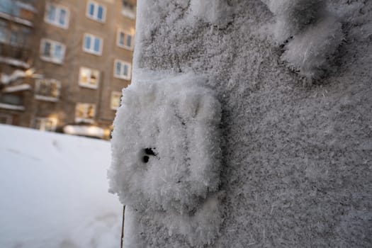 Closeup of snow and hoarfrost covering wall of building on urban street in cold winter weather