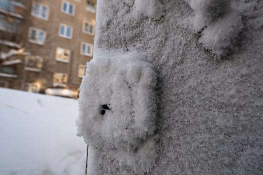 Closeup of snow and hoarfrost covering wall of building on urban street in cold winter weather