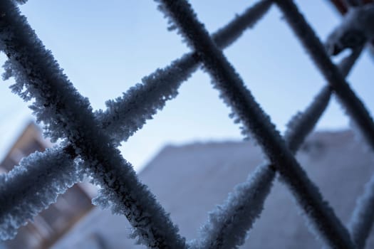 Metal wire door door are covered with frost - icy lock covered with snowflakes - concept of cold winter