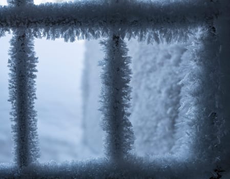 Closeup of window bars covered with white snow and hoarfrost in cold winter day