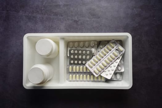 Various medication bottles and packs are arranged on a gray surface.