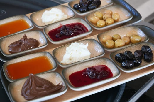 Assorted spreads and olives arranged neatly on a wooden platter.