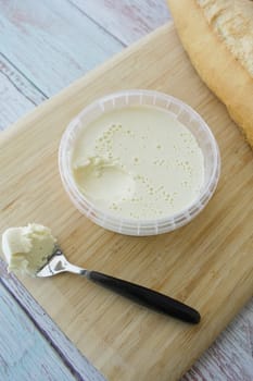 A delicious creamy spread is placed beside warm bread on a cutting board.