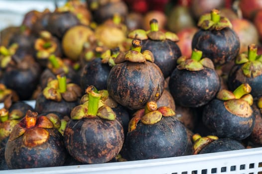 harvest of ripe mangosteen on counter at a street market in Asia in Thailand close-up