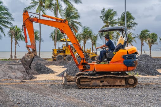 excavator at a gravel construction site on a beach by the sea performs excavation work on construction in Asia