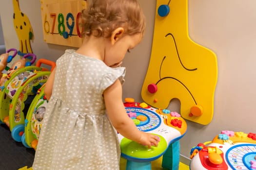 Toddler enjoying a vibrant playroom filled with colorful toys and an educational activity table. Concept of interactive play and fostering childhood development through fun learning experiences