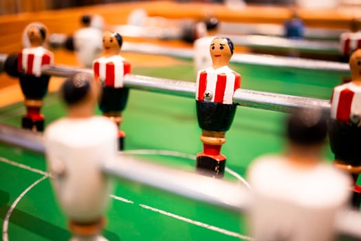 Table soccer game close up with red and white team figures on green field.