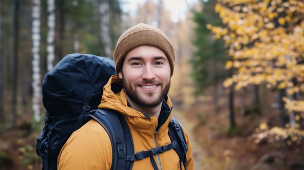 Travel, hiking, adventure, portrait of happy traveler hiker young man with backpack stands in autumn forest with yellow leaves, looking at camera