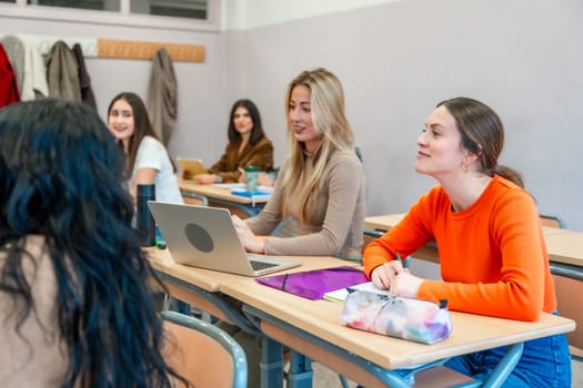 Group of female university students listening attentively to a lecture in a classroom, engaging with the educational material and using a laptop