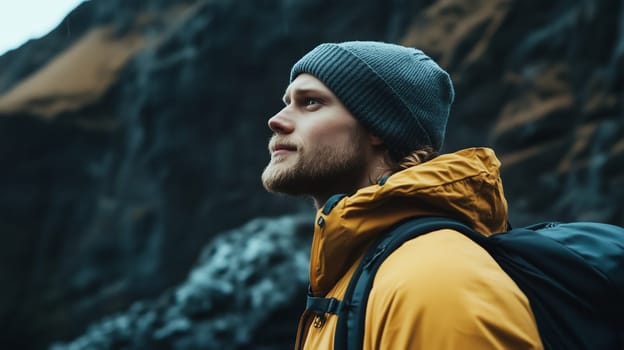 Travel, hiking, adventure, portrait of traveler hiker young man in jacket stands on top of mountain looking away