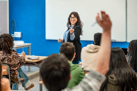 University professor pointing at a student raising hand to answer a question during a lesson in classroom