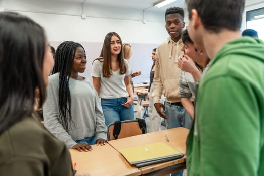 Diverse group of university students engaged in teamwork, discussing and sharing ideas around a desk in a classroom setting