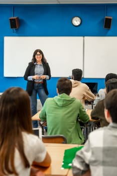 Cheerful professor is teaching a lesson to a diverse group of university students in a modern classroom