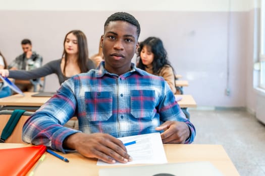 Young black man concentrating on his studies in a university classroom, surrounded by fellow students from diverse backgrounds