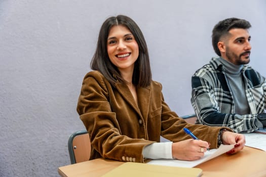 Smiling female student taking notes in class at university, fully engaged in learning and focused on her academic success