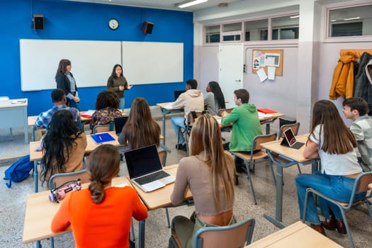 Multi ethnic group of high school students attending a lecture held by two teachers in a classroom at their university institute
