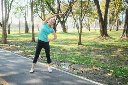 Smiling young woman stretching her body after exercising in a park.