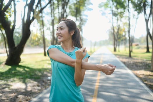 Beautiful young woman stretching arms before outdoor workout.