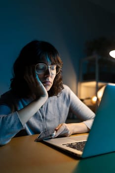 Tired and overworked woman falling asleep while working with laptop at home office. Vertical. Lifestyle concept.