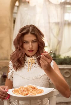 Beautiful girl enjoys her life under canopies or baldachin in resort or hotel stock photo. Woman eats spaghetti in an exclusive resort. High quality photo