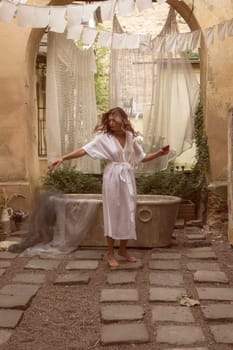 young slim woman dancing in the courtyard in the old city. in the background fabric, and marble antique bathtub. A person standing in front of a building. High quality photo
