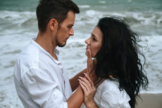 young beautiful couple in love hugging on the beach by the sea in summer close up