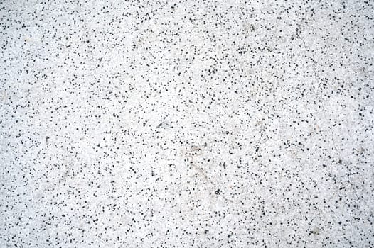 grainy abstract white texture with crumbs of black stones. The pattern of the sidewalk surface