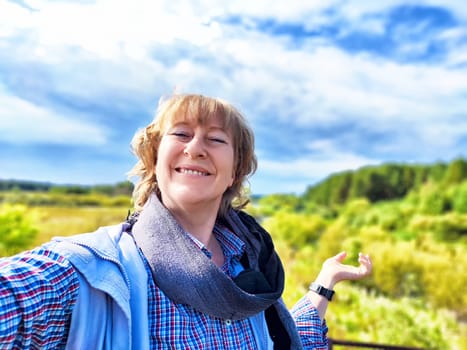 A middle-aged female traveler captures her joyful moment in nature during an exciting trip in a picturesque landscape.