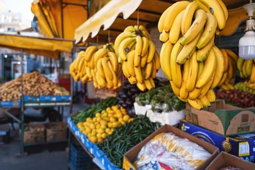 Aqaba, Jordan - January 17, 2020: Bananas, lemons and green beans displayed on local fruit and vegetables market. Shallow depth of field photo, only yellow fruits in focus