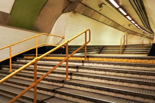 Stairs and yellow rail leading to underground train tunnel