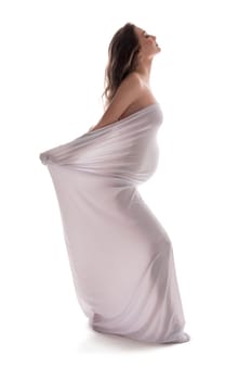 Naked serene pregnant female wrapped in cloth walking with closed eyes on white background in studio