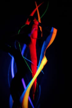 Artwork portrait of alluring young nude female model standing in dark studio with creative multicolored neon illumination